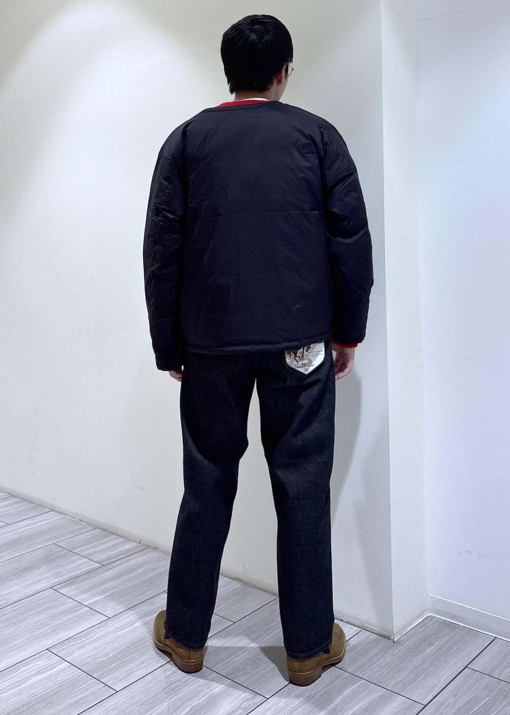 レッド系のカーディガン/ボレロ、ブラック系のダウンジャケット/コート、ブラック系のデニムパンツを着用したメンズの冬コーディネートの3枚目の写真