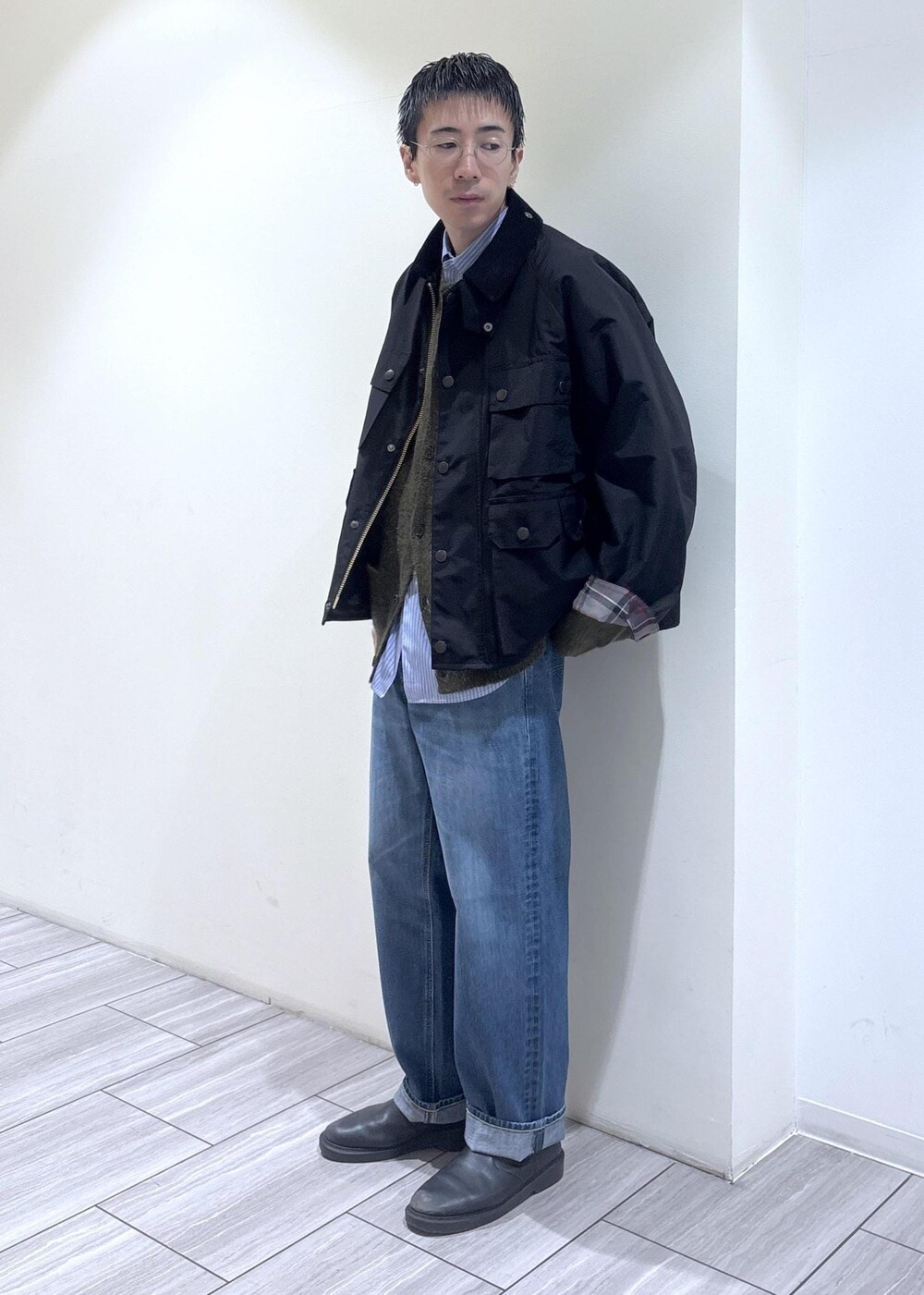 ブルー系のデニムパンツ、ブラック系のブルゾン、グリーン系のカーディガン/ボレロを着用したメンズの秋コーディネートの3枚目の写真