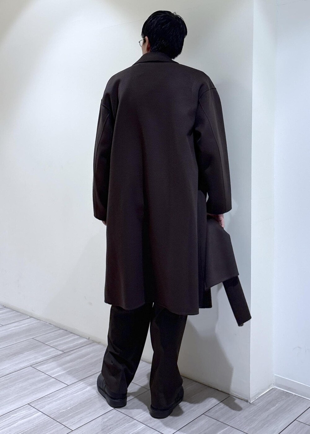 ブラウン系のスラックス、ブラウン系のステンカラーコート、ホワイト系のTシャツ/カットソーを着用したメンズの秋コーディネートの3枚目の写真