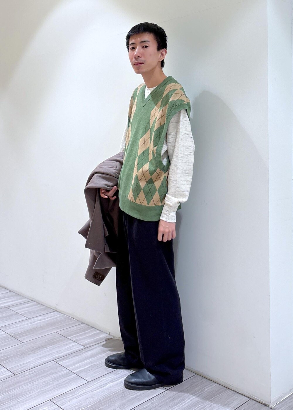 ホワイト系のスウェット、グリーン系のベストを着用したメンズの冬コーディネートの2枚目の写真