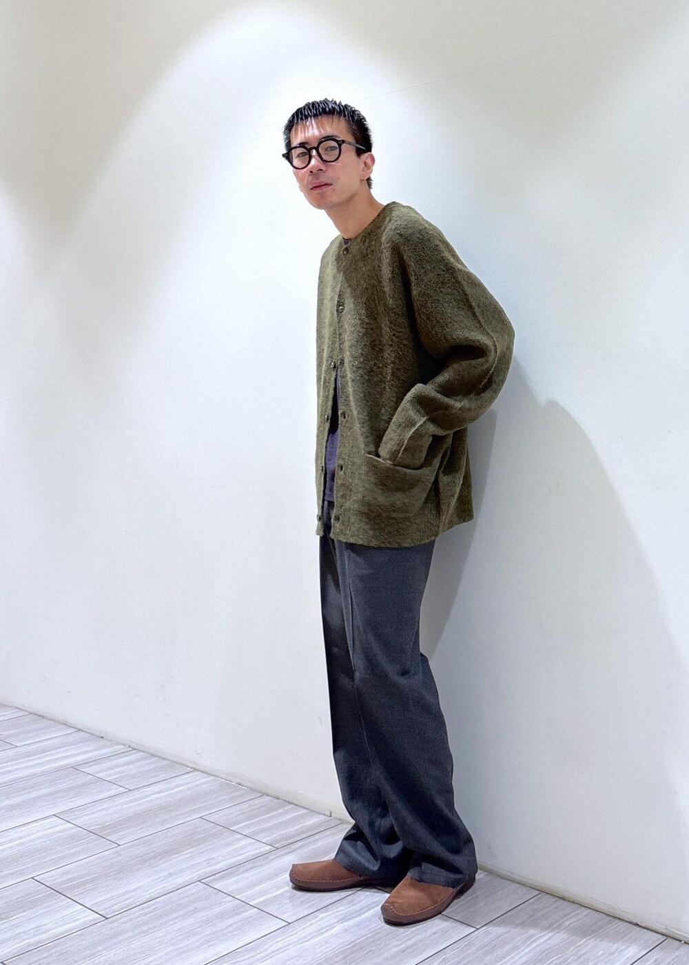 グリーン系のカーディガン/ボレロ、ブラウン系のスリッポン、グレー系のスラックスを着用したメンズの秋コーディネートの3枚目の写真