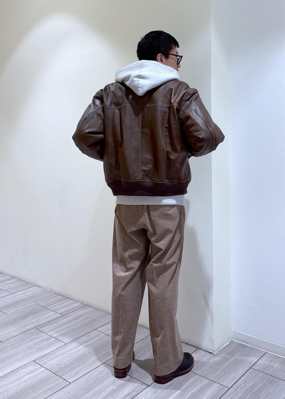 ブラック系のブーツ、グレー系のパーカー、ベージュ系のスラックスを着用したメンズの秋コーディネートの4枚目の写真