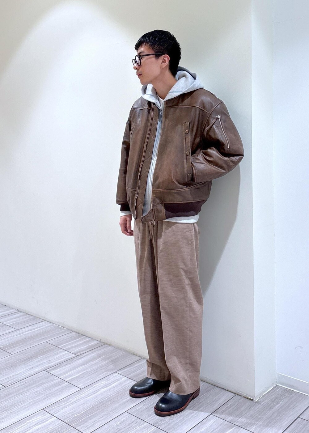 ブラック系のブーツ、グレー系のパーカー、ベージュ系のスラックスを着用したメンズの秋コーディネートの3枚目の写真