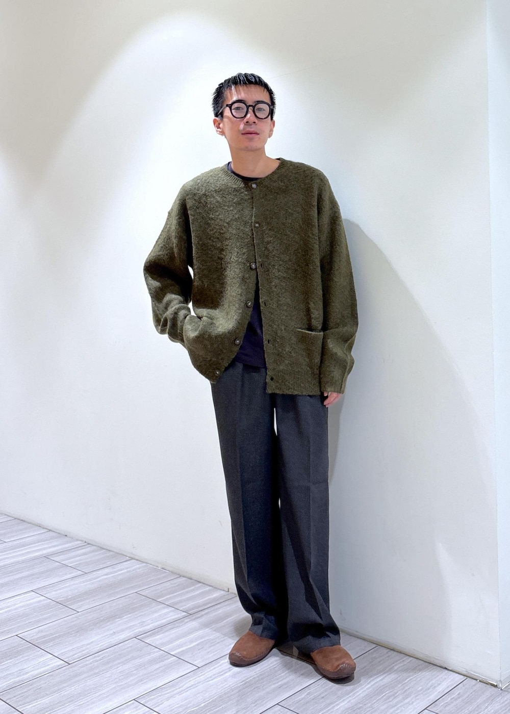 グリーン系のカーディガン/ボレロ、ブラウン系のスリッポン、グレー系のスラックスを着用したメンズの秋コーディネートの2枚目の写真