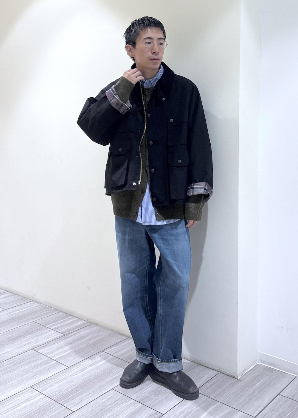 ブルー系のデニムパンツ、ブラック系のブルゾン、グリーン系のカーディガン/ボレロを着用したメンズの秋コーディネートの2枚目の写真