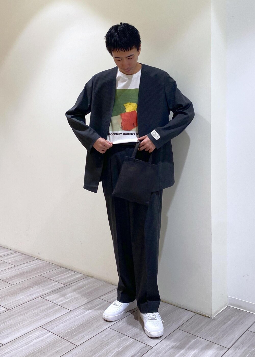 グレー系のノーカラージャケット、グレー系のスラックス、ホワイト系のスニーカーを着用したメンズの秋コーディネートの3枚目の写真