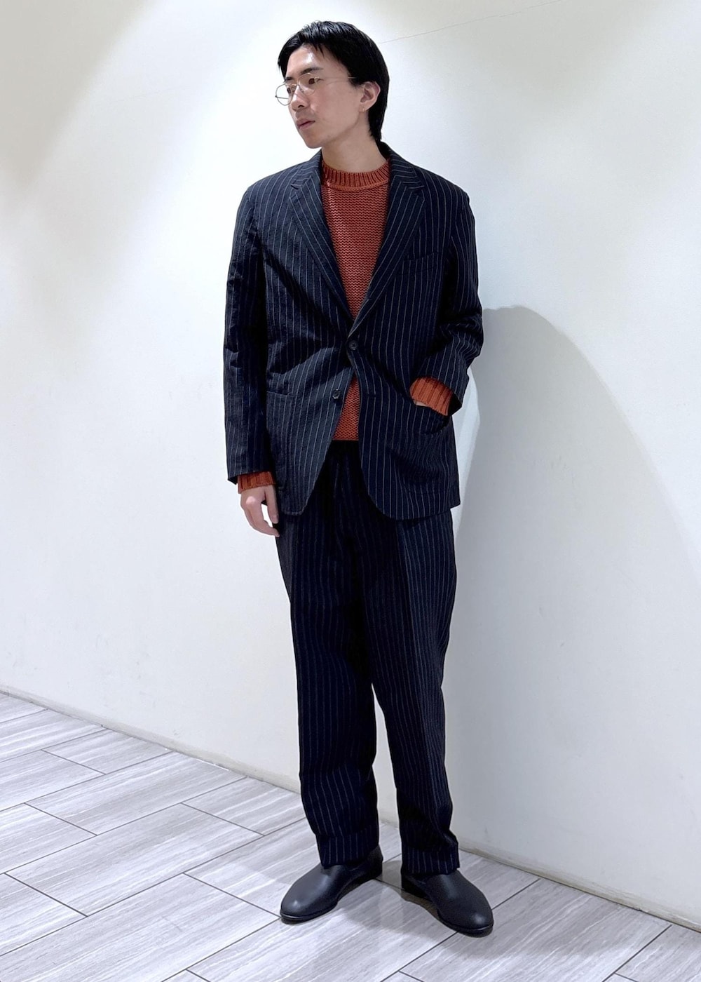 ブルー系のスラックス、ブルー系のノーカラージャケット、オレンジ系のニット/セーターを着用したメンズの冬コーディネートの2枚目の写真