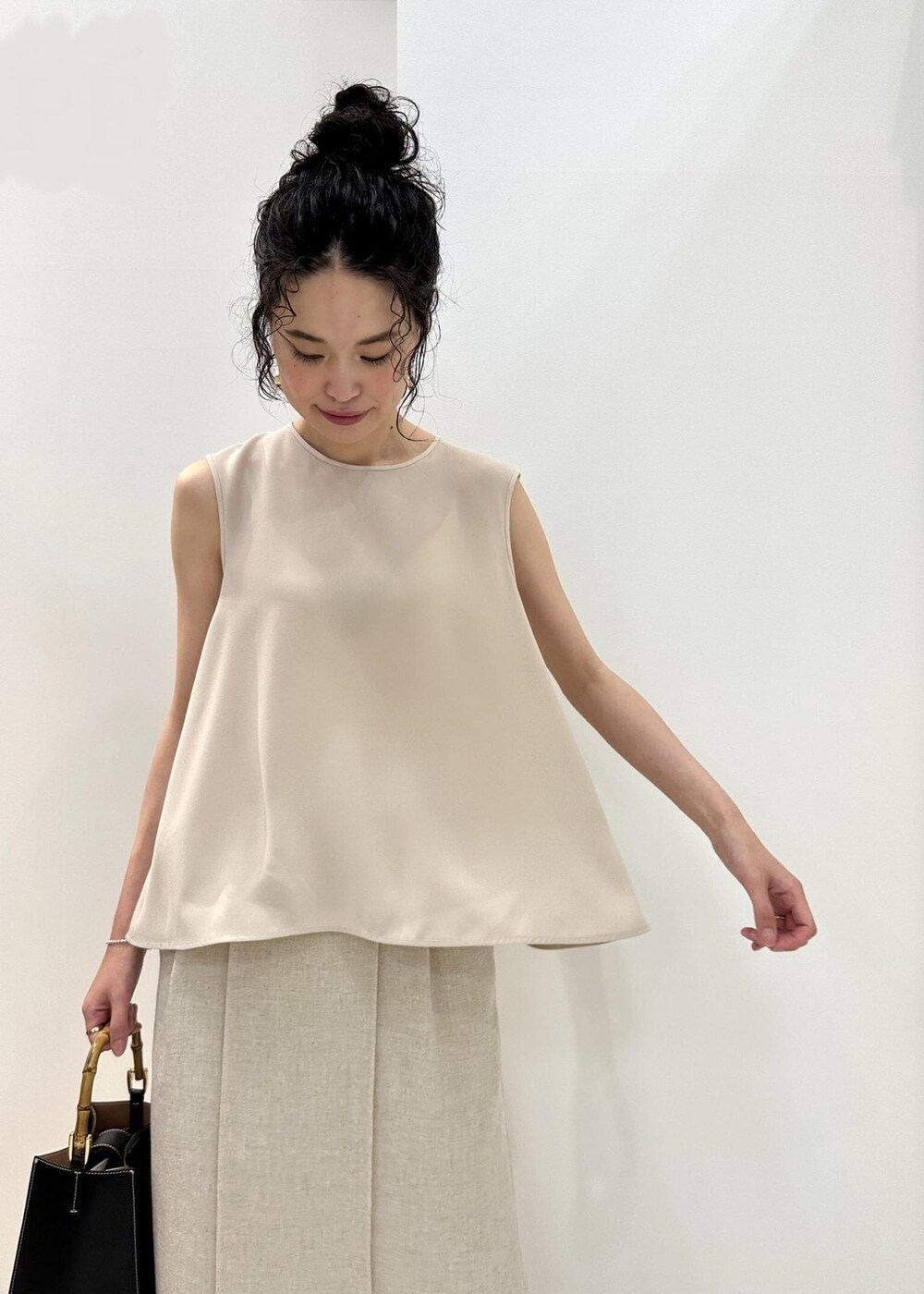 ブラック系のハンドバッグ、ブラック系のサンダル、ベージュ系のシャツ/ブラウスを着用したレディースの夏コーディネートの4枚目の写真