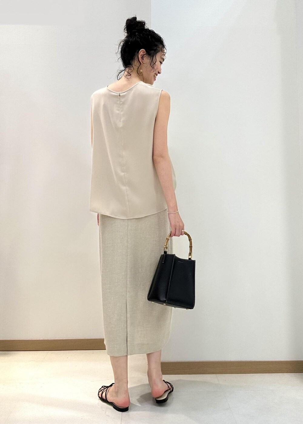 ブラック系のハンドバッグ、ブラック系のサンダル、ベージュ系のシャツ/ブラウスを着用したレディースの夏コーディネートの3枚目の写真