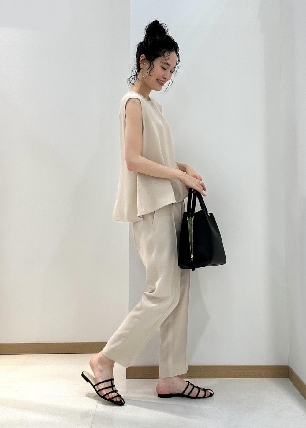 ブラック系のハンドバッグ、ブラック系のサンダル、ベージュ系のシャツ/ブラウスを着用したレディースの夏コーディネートの2枚目の写真