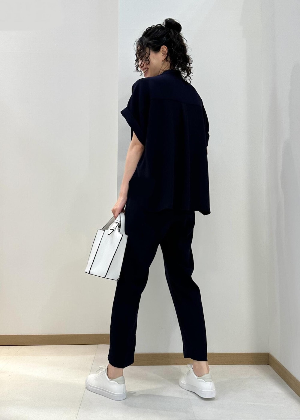 ホワイト系のハンドバッグ、ホワイト系のスニーカー、ブルー系のその他パンツを着用したレディースの夏コーディネートの3枚目の写真