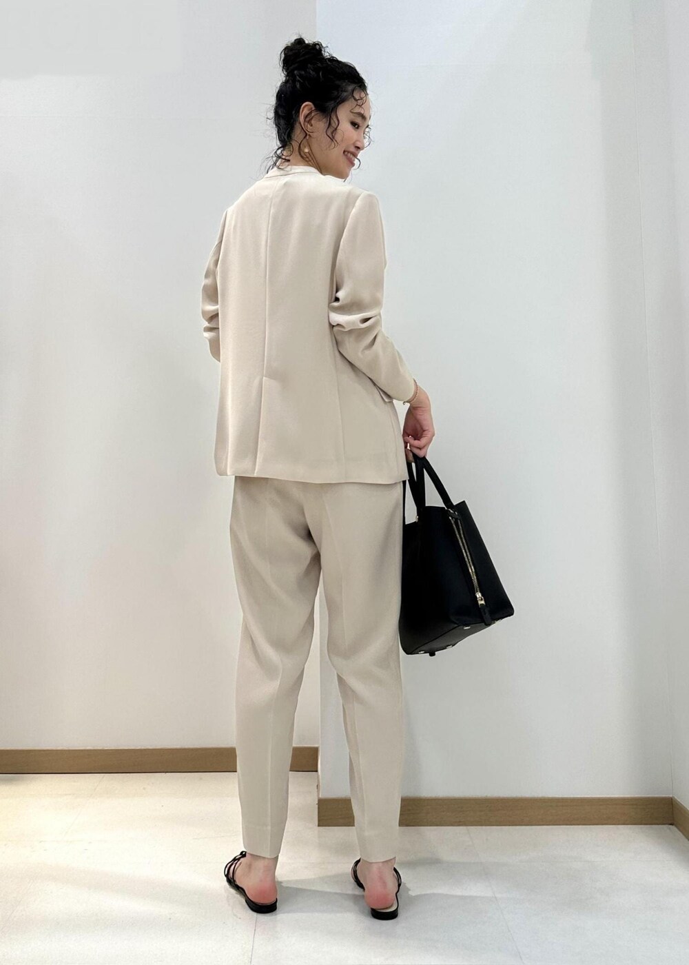 ブラック系のハンドバッグ、ブラック系のサンダル、ベージュ系のシャツ/ブラウスを着用したレディースの夏コーディネートの3枚目の写真