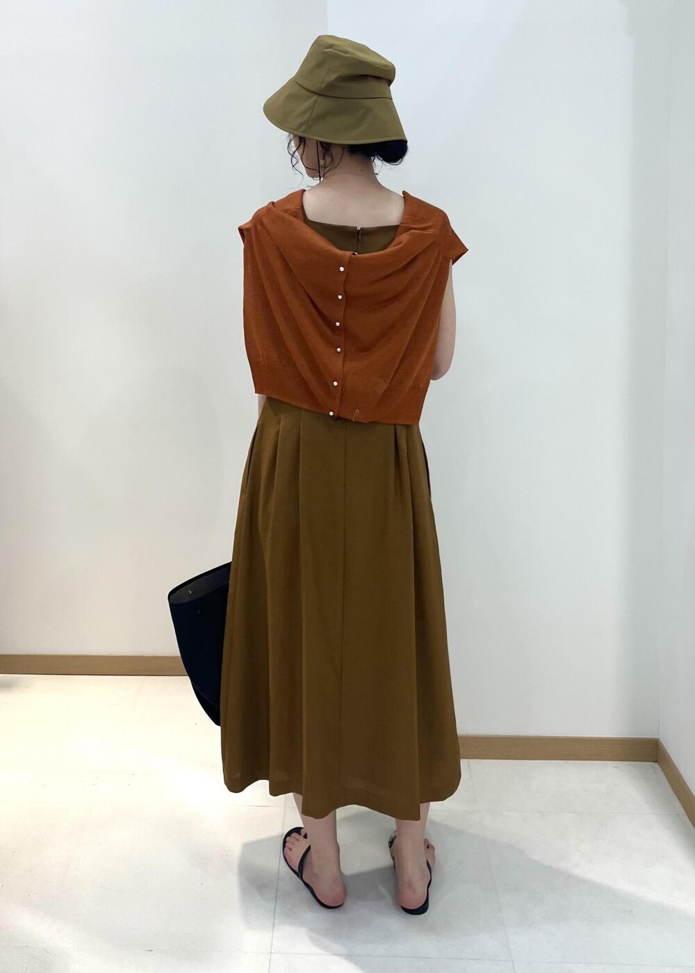 ブラック系のハンドバッグ、ブラック系のサンダル、オレンジ系のカーディガン/ボレロを着用したレディースの夏コーディネートの3枚目の写真