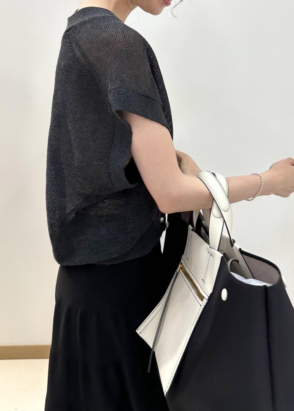 ブラック系のハンドバッグ、ホワイト系のサンダル、ブラック系のスカートを着用したレディースの夏コーディネートの5枚目の写真