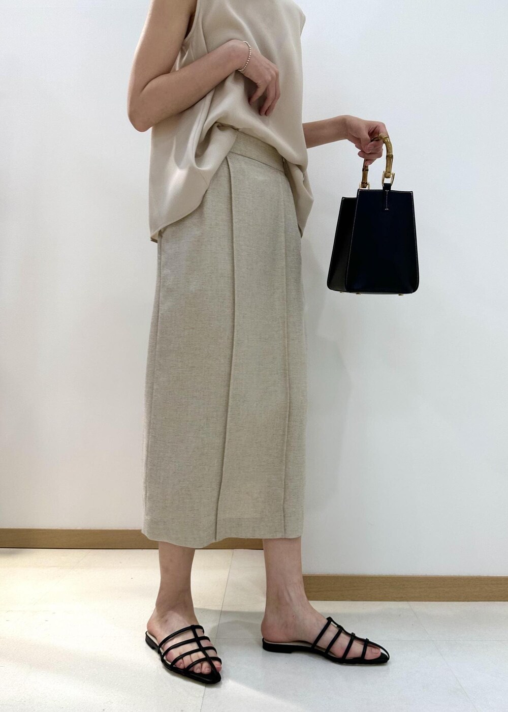 ブラック系のハンドバッグ、ブラック系のサンダル、ベージュ系のシャツ/ブラウスを着用したレディースの夏コーディネートの7枚目の写真