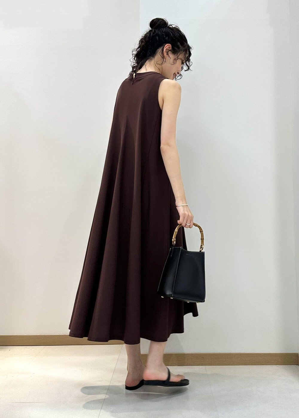 ブラック系のハンドバッグ、ブラック系のサンダル、ブラウン系のワンピースを着用したレディースの夏コーディネートの3枚目の写真
