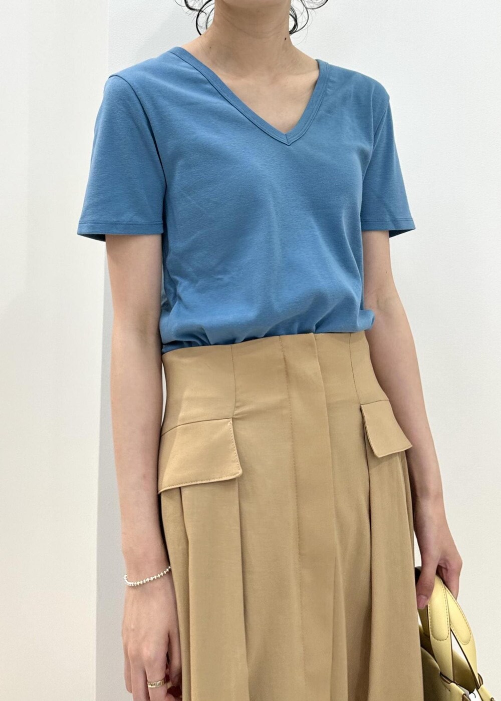 イエロー系のハンドバッグ、ベージュ系のサンダル、ベージュ系のスカートを着用したレディースの夏コーディネートの5枚目の写真