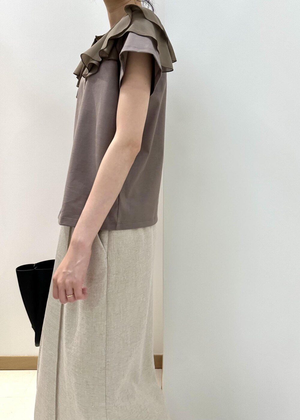 ブラック系のトートバッグ、ブラック系のサンダル、ベージュ系のTシャツ/カットソーを着用したレディースの夏コーディネートの6枚目の写真