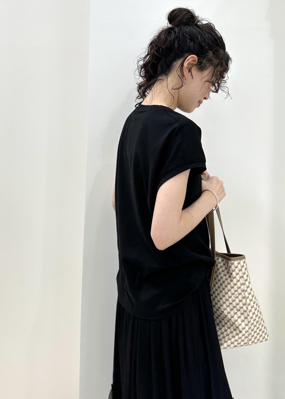 ベージュ系のトートバッグ、ホワイト系のサンダル、ブラック系のTシャツ/カットソーを着用したレディースの夏コーディネートの6枚目の写真