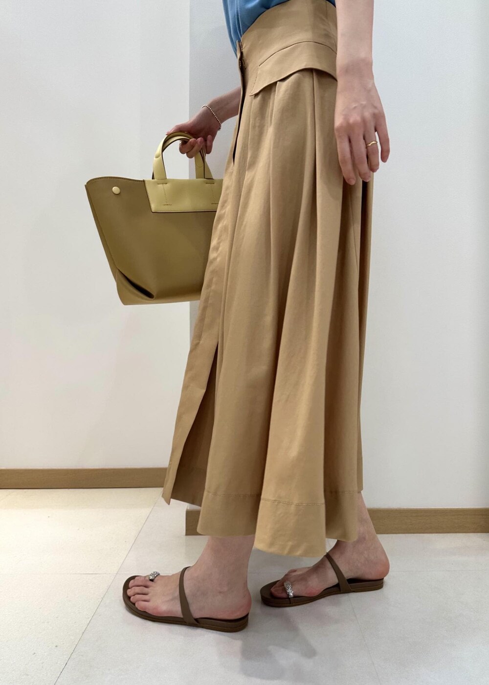 イエロー系のハンドバッグ、ベージュ系のサンダル、ベージュ系のスカートを着用したレディースの夏コーディネートの7枚目の写真