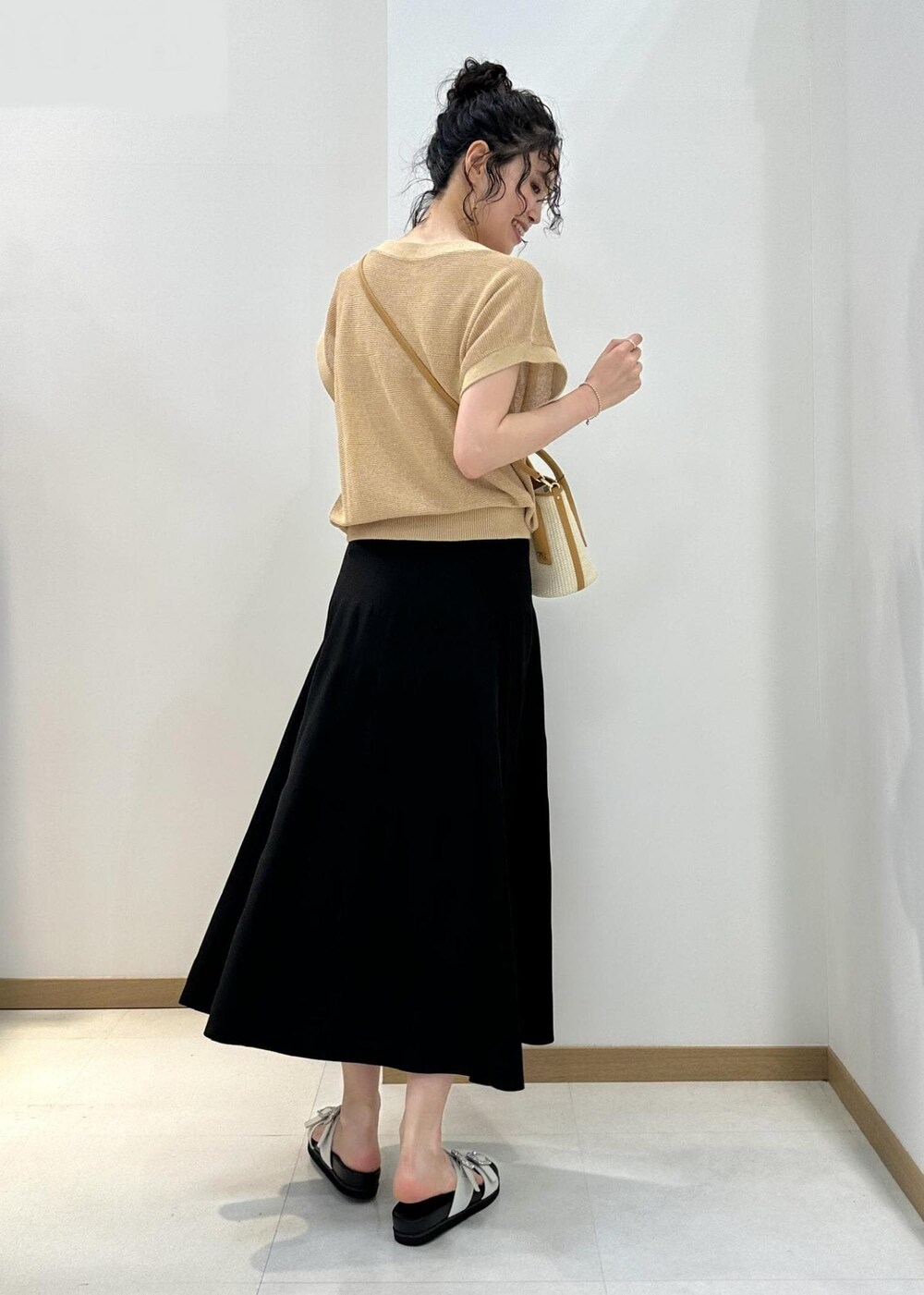 ベージュ系のハンドバッグ、ホワイト系のサンダル、ブラック系のスカートを着用したレディースの夏コーディネートの3枚目の写真