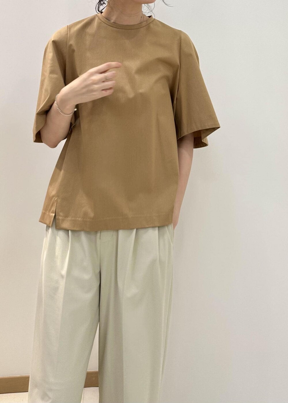 ブラック系のハンドバッグ、ブラック系のサンダル、ベージュ系のTシャツ/カットソーを着用したレディースの夏コーディネートの5枚目の写真