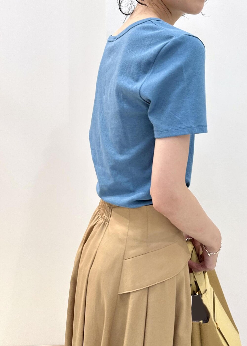 イエロー系のハンドバッグ、ベージュ系のサンダル、ベージュ系のスカートを着用したレディースの夏コーディネートの6枚目の写真