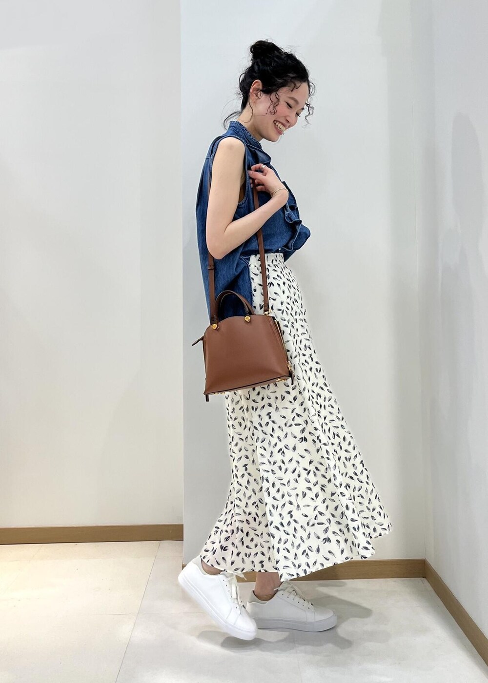 ブラウン系のハンドバッグ、ブルー系のシャツ/ブラウス、ホワイト系のスカートを着用したレディースの春コーディネートの2枚目の写真