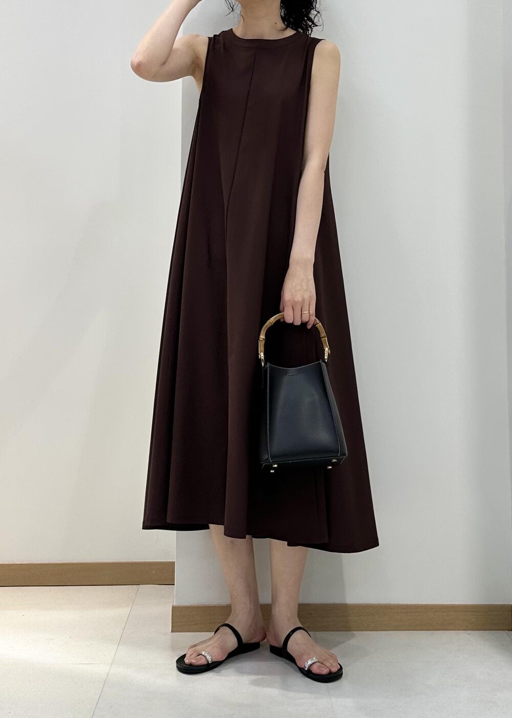 ブラック系のハンドバッグ、ブラック系のサンダル、ブラウン系のワンピースを着用したレディースの夏コーディネートの4枚目の写真