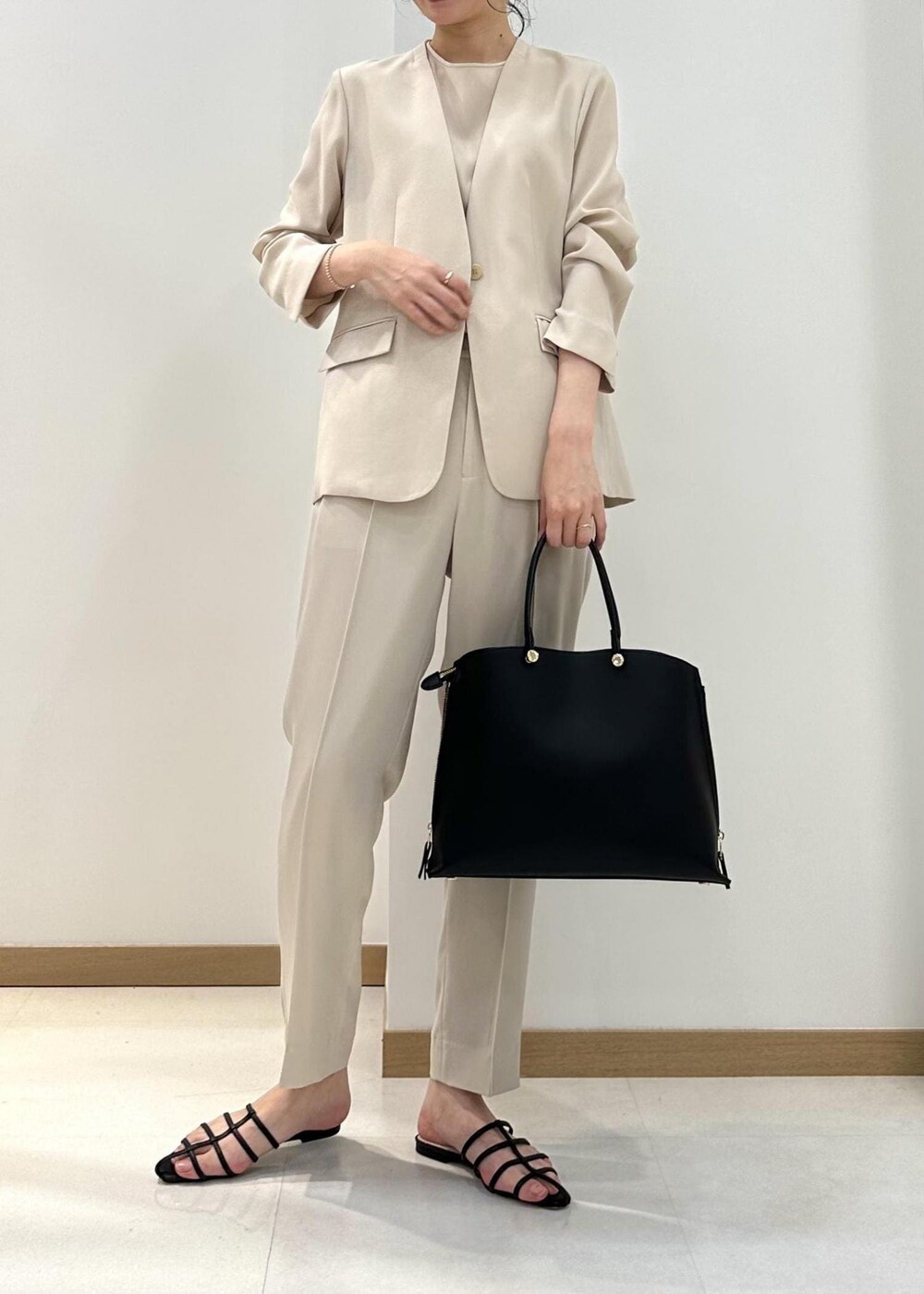ブラック系のハンドバッグ、ブラック系のサンダル、ベージュ系のシャツ/ブラウスを着用したレディースの夏コーディネートの4枚目の写真