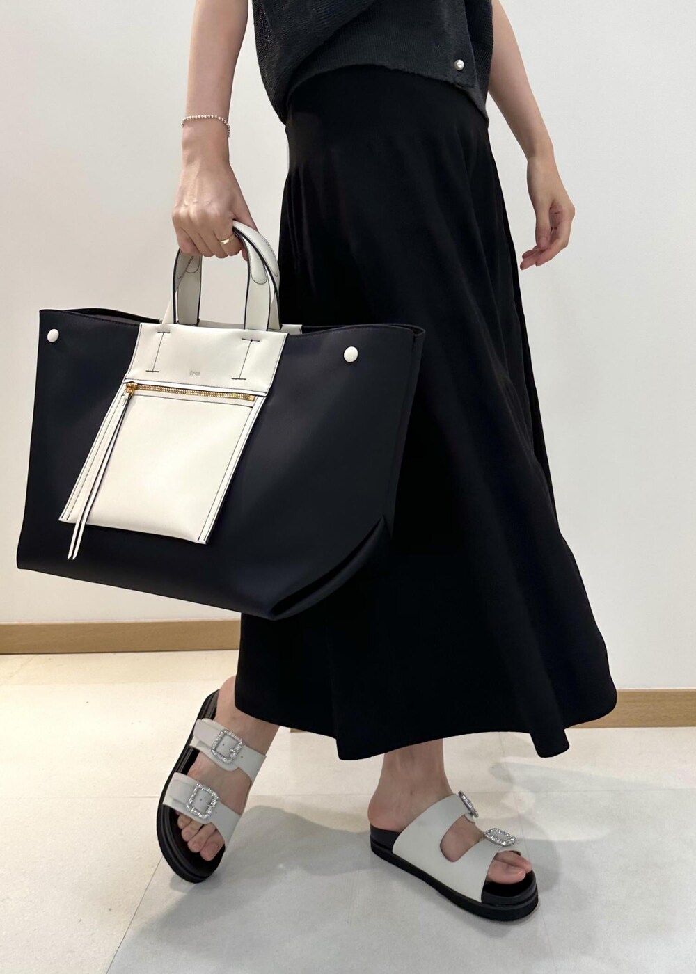 ブラック系のハンドバッグ、ホワイト系のサンダル、ブラック系のスカートを着用したレディースの夏コーディネートの6枚目の写真