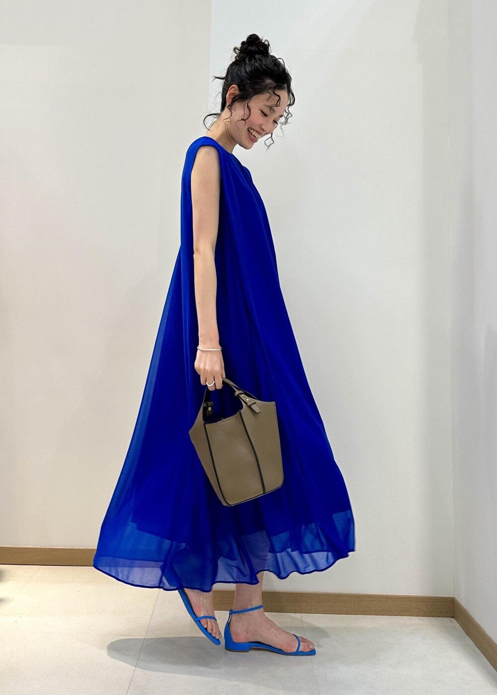 ベージュ系のハンドバッグ、ブルー系のサンダル、ブルー系のワンピースを着用したレディースの夏コーディネートの2枚目の写真