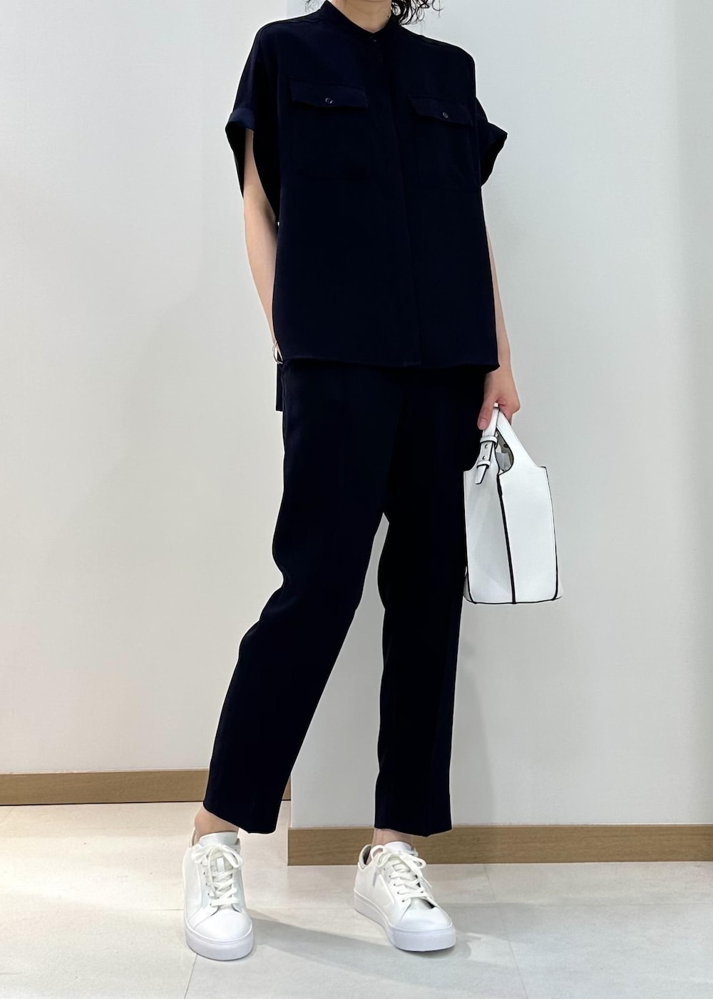 ホワイト系のハンドバッグ、ホワイト系のスニーカー、ブルー系のその他パンツを着用したレディースの夏コーディネートの4枚目の写真
