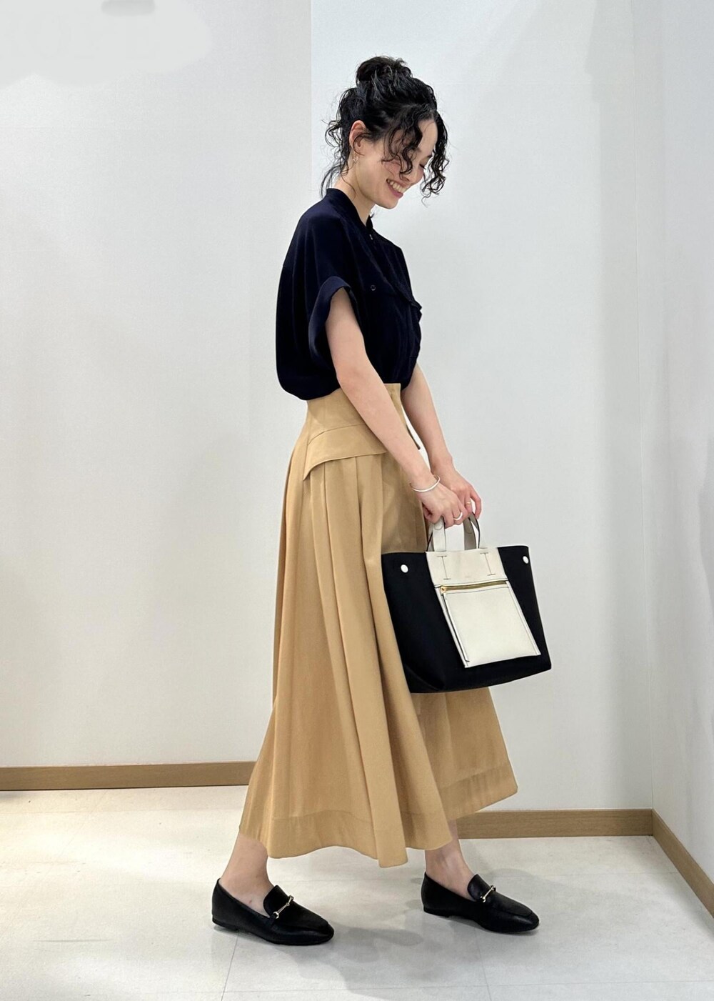 ブラック系のハンドバッグ、ブラック系のレインシューズ、ブルー系のシャツ/ブラウスを着用したレディースの夏コーディネートの2枚目の写真