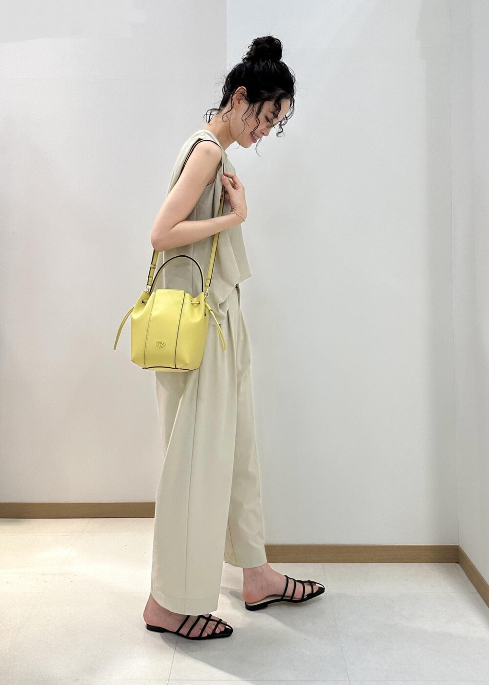 ブラック系のサンダル、ベージュ系のハンドバッグ、ベージュ系のシャツ/ブラウスを着用したレディースの夏コーディネートの2枚目の写真