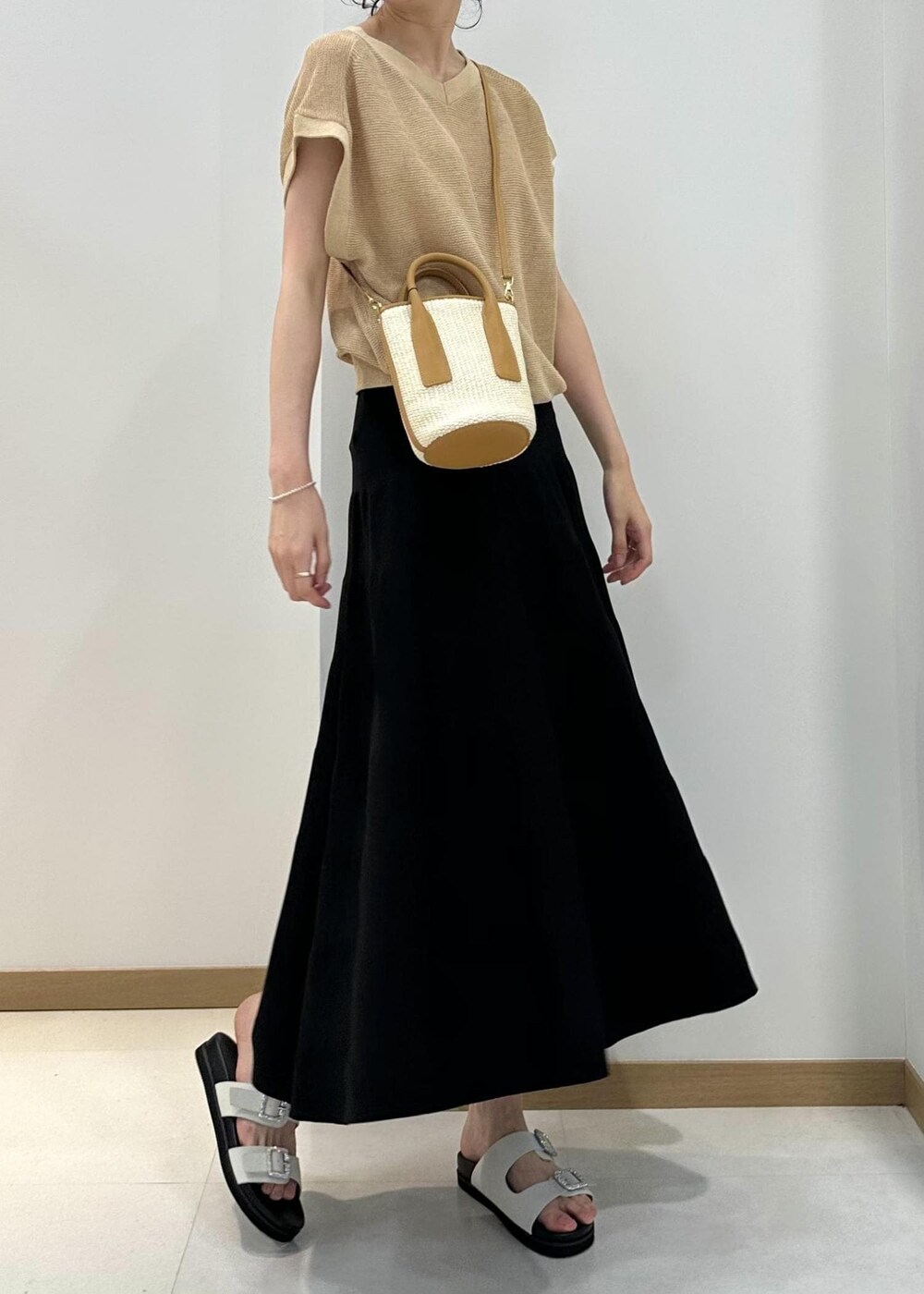 ベージュ系のハンドバッグ、ホワイト系のサンダル、ブラック系のスカートを着用したレディースの夏コーディネートの4枚目の写真