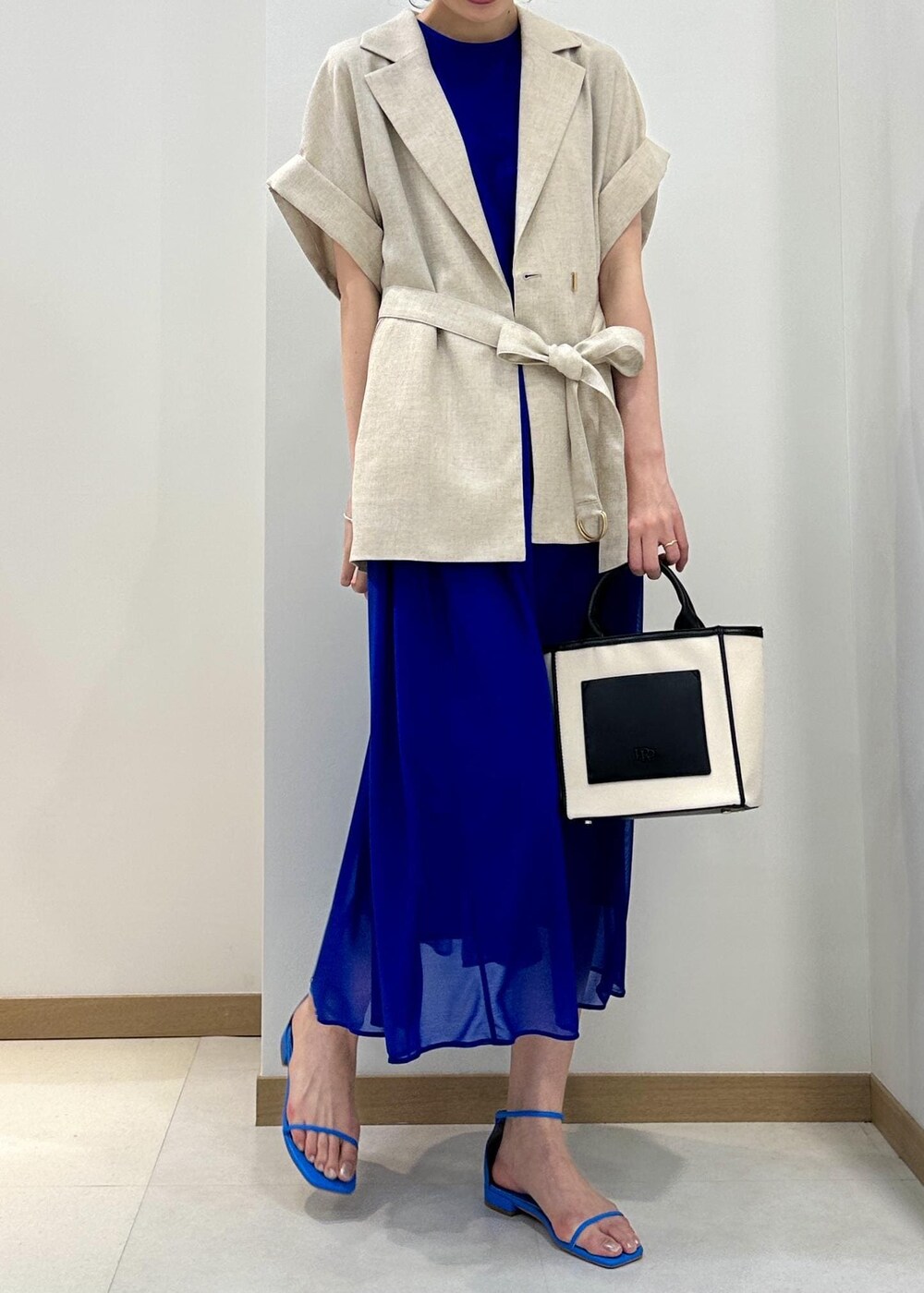 ブラック系のトートバッグ、ブルー系のサンダル、ブルー系のワンピースを着用したレディースの春コーディネートの4枚目の写真