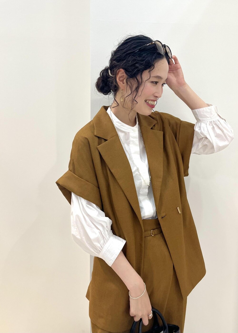 ブラック系のパンプス、ブラック系のトートバッグ、ホワイト系のシャツ/ブラウスを着用したレディースの夏コーディネートの6枚目の写真