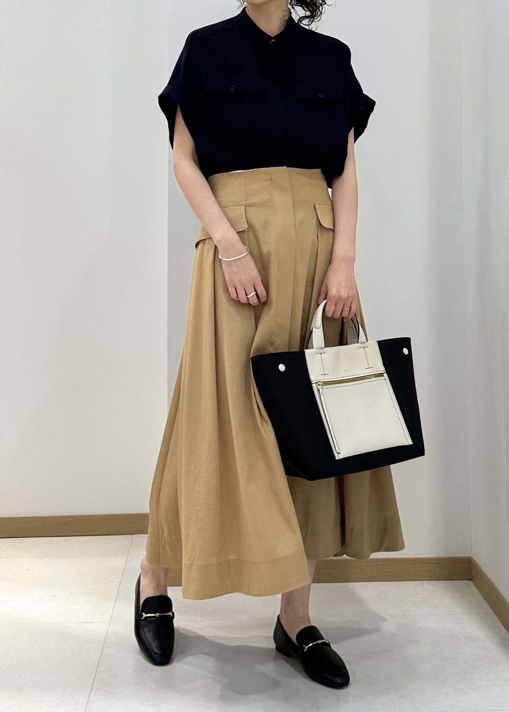 ブラック系のハンドバッグ、ブラック系のレインシューズ、ブルー系のシャツ/ブラウスを着用したレディースの夏コーディネートの4枚目の写真