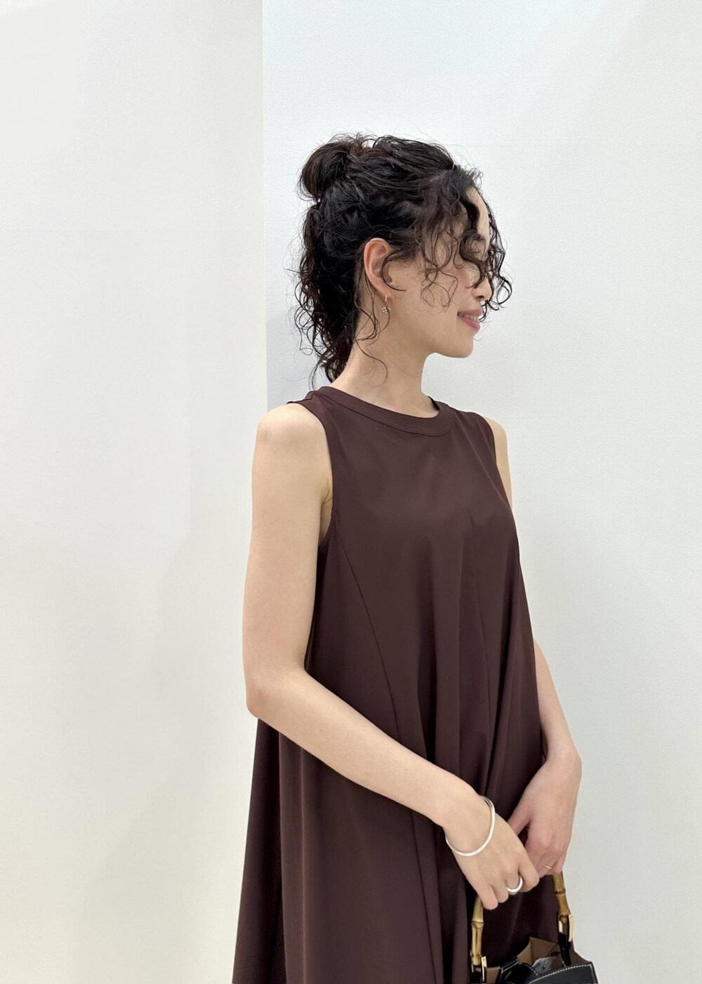 ブラック系のハンドバッグ、ブラック系のサンダル、ブラウン系のワンピースを着用したレディースの夏コーディネートの6枚目の写真