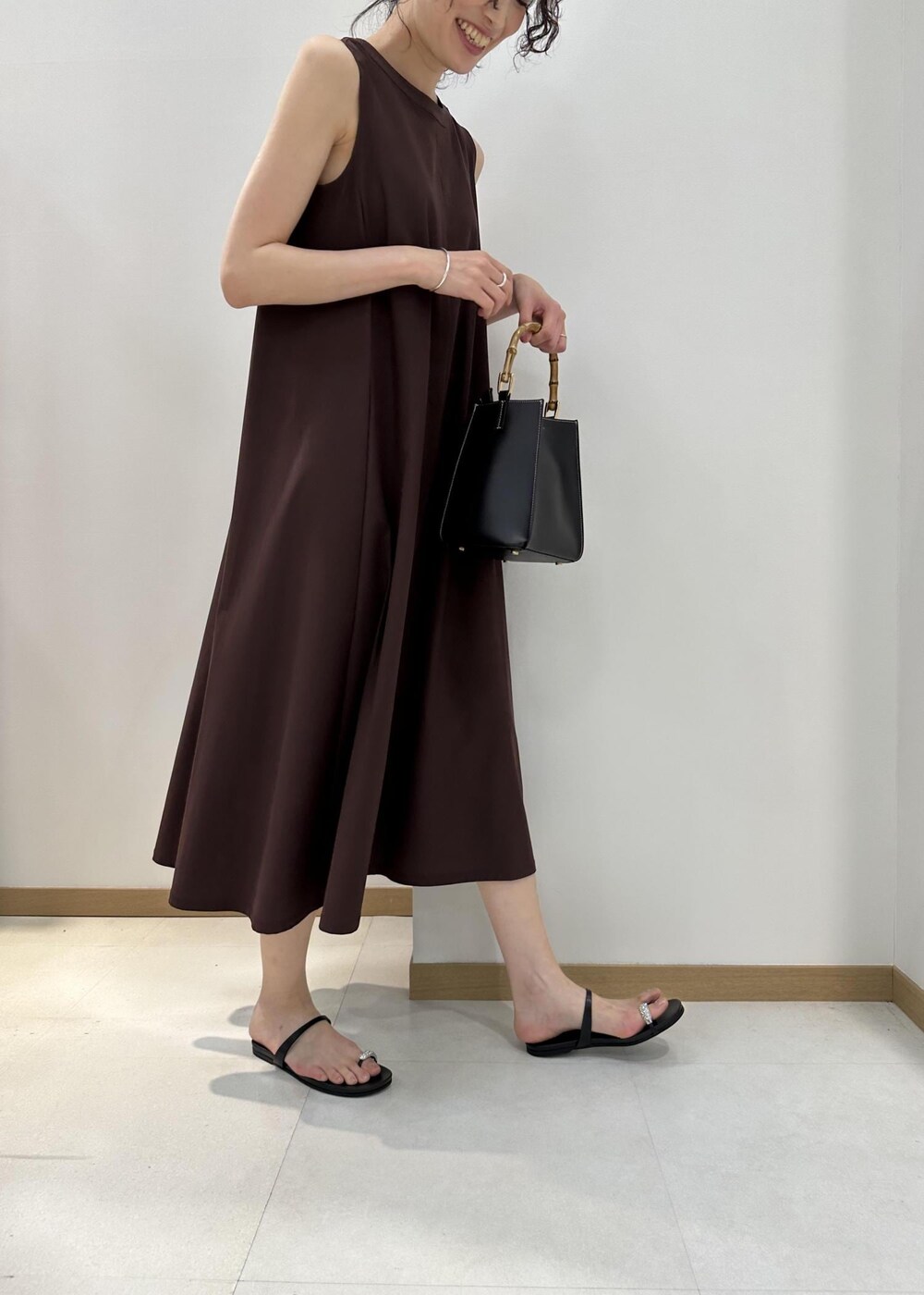 ブラック系のハンドバッグ、ブラック系のサンダル、ブラウン系のワンピースを着用したレディースの夏コーディネートの5枚目の写真