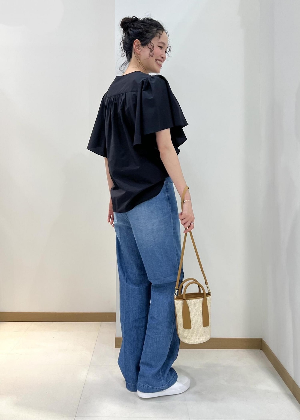 ベージュ系のハンドバッグ、ブルー系のデニムパンツ、ブラック系のシャツ/ブラウスを着用したレディースの春コーディネートの3枚目の写真