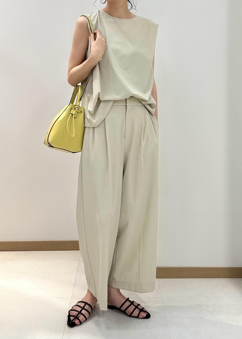 ブラック系のサンダル、ベージュ系のハンドバッグ、ベージュ系のシャツ/ブラウスを着用したレディースの夏コーディネートの4枚目の写真