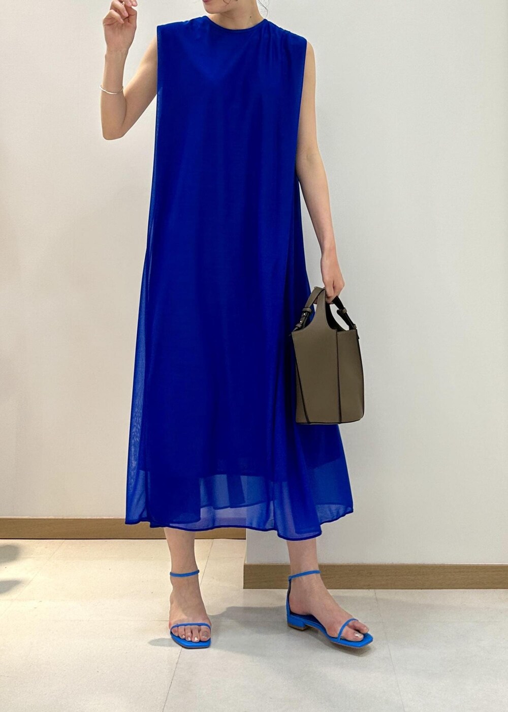 ベージュ系のハンドバッグ、ブルー系のサンダル、ブルー系のワンピースを着用したレディースの夏コーディネートの4枚目の写真