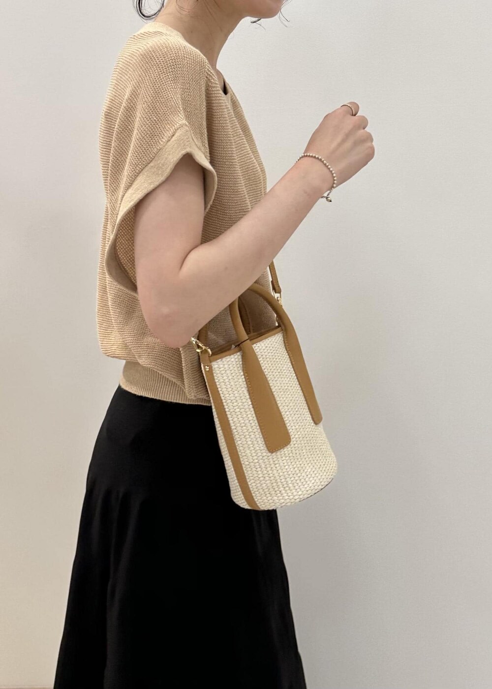 ベージュ系のハンドバッグ、ホワイト系のサンダル、ブラック系のスカートを着用したレディースの夏コーディネートの6枚目の写真