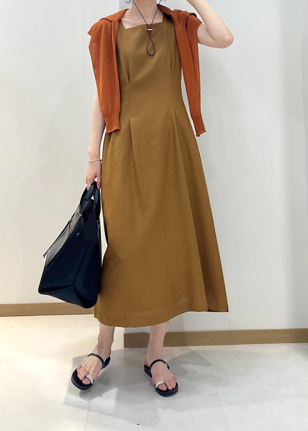 ブラック系のハンドバッグ、ブラック系のサンダル、オレンジ系のカーディガン/ボレロを着用したレディースの夏コーディネートの4枚目の写真