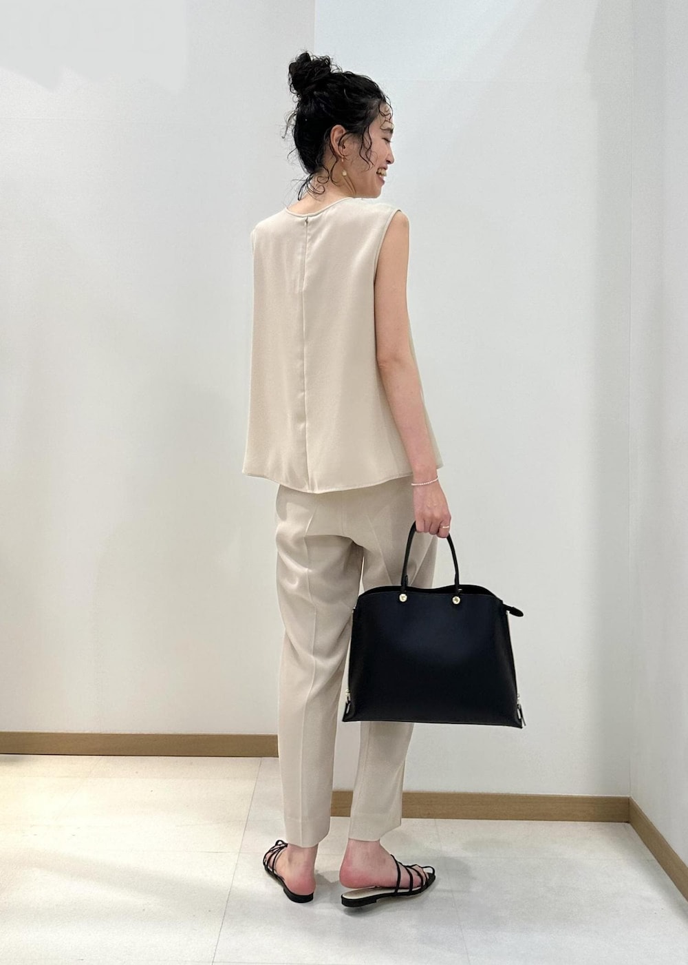 ブラック系のハンドバッグ、ブラック系のサンダル、ベージュ系のシャツ/ブラウスを着用したレディースの夏コーディネートの3枚目の写真