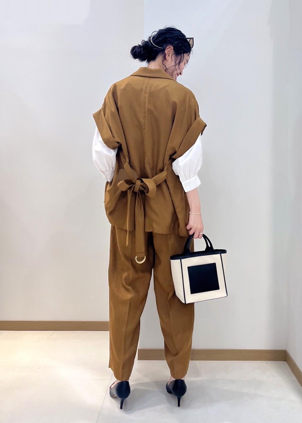 ブラック系のパンプス、ブラック系のトートバッグ、ホワイト系のシャツ/ブラウスを着用したレディースの夏コーディネートの3枚目の写真