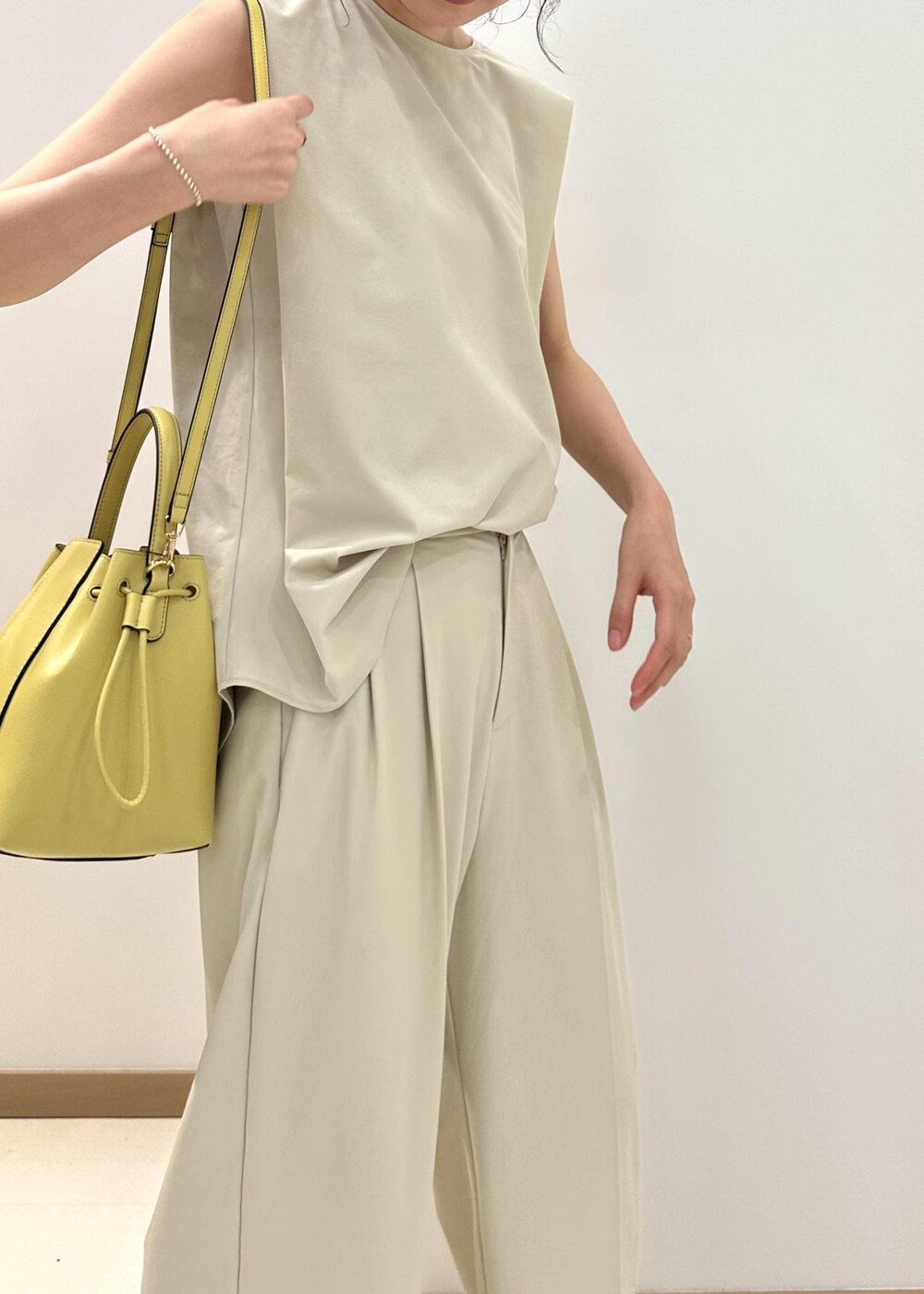 ブラック系のサンダル、ベージュ系のハンドバッグ、ベージュ系のシャツ/ブラウスを着用したレディースの夏コーディネートの5枚目の写真