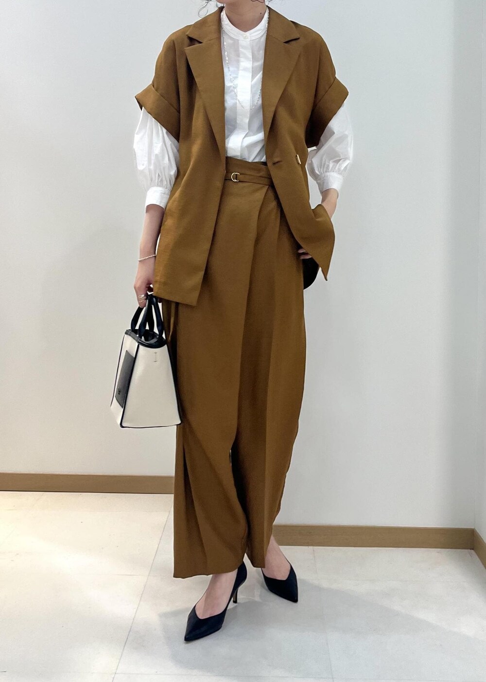 ブラック系のパンプス、ブラック系のトートバッグ、ホワイト系のシャツ/ブラウスを着用したレディースの夏コーディネートの4枚目の写真